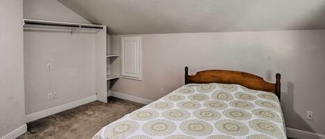 A bedroom with a bed, a closet, and a slanted ceiling.