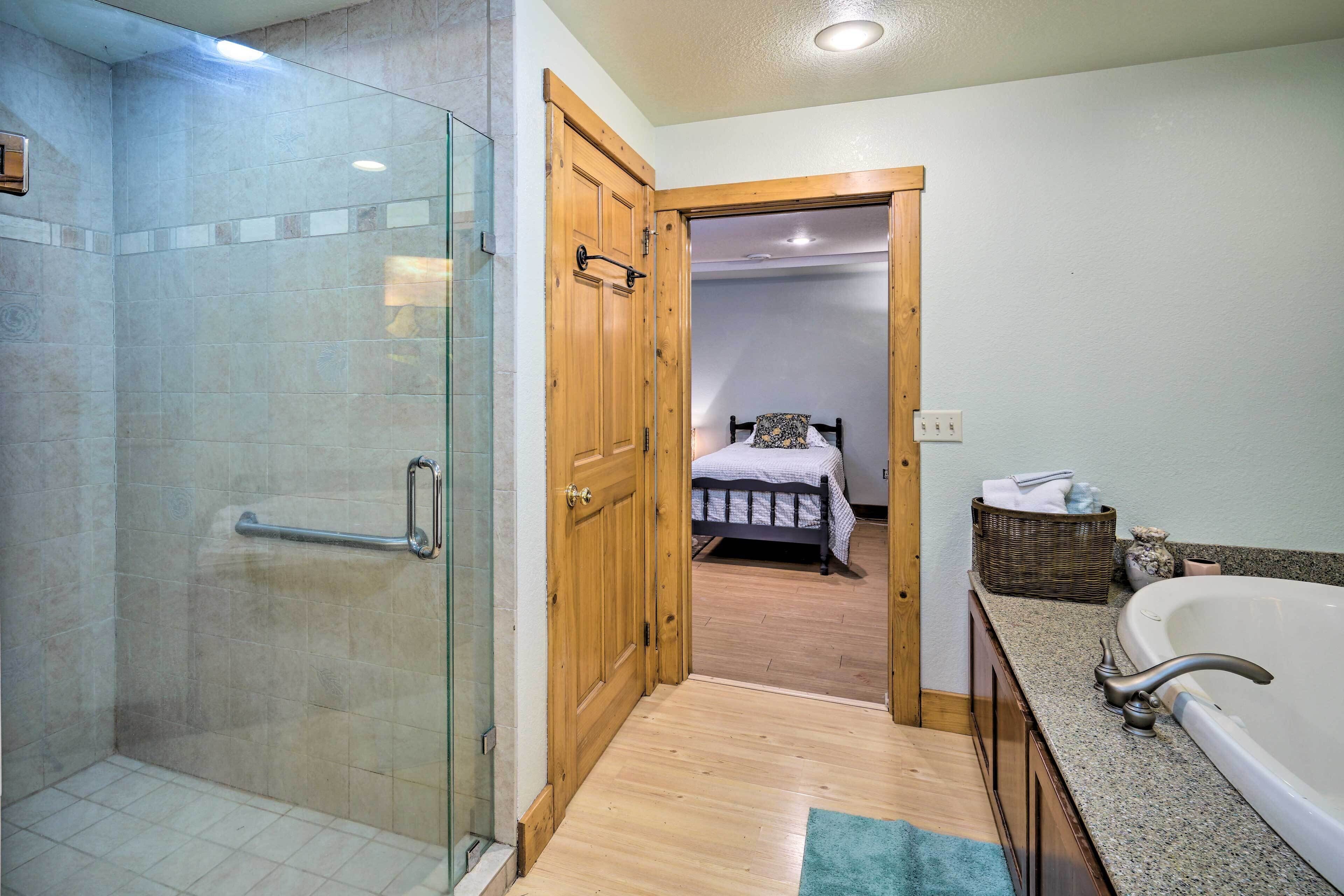 A bathroom with a glass shower enclosure, wooden door, and a bathtub.