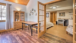 A cozy room with a wooden floor, a wooden cabinet, a dining table, and a bed.