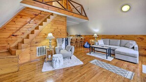 A loft-style room with a wooden staircase, a gray sofa, and a dining area. - Cozy Yatesville Lake Cabin Rental in Louisa! (Louisa)