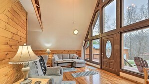 A cozy room with wooden walls, a sofa, a table, and a lamp. - Cozy Yatesville Lake Cabin Rental in Louisa! (Louisa)