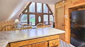 A kitchen with a marble countertop, wooden cabinets, a black refrigerator, and large windows offering a view of the outdoors. - Cozy Yatesville Lake Cabin Rental in Louisa! (Louisa)