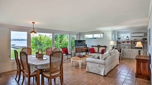A spacious living area with a dining table, chairs, a sofa, and a kitchen area with a grill. - Waterfront Vacation Rental on Lake Mirror! (Winter Haven)