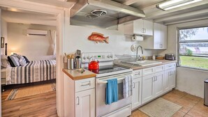 A compact kitchen with white cabinets, a red kettle, and a fish decoration on the wall. - Waterfront Vacation Rental on Lake Mirror! (Winter Haven)