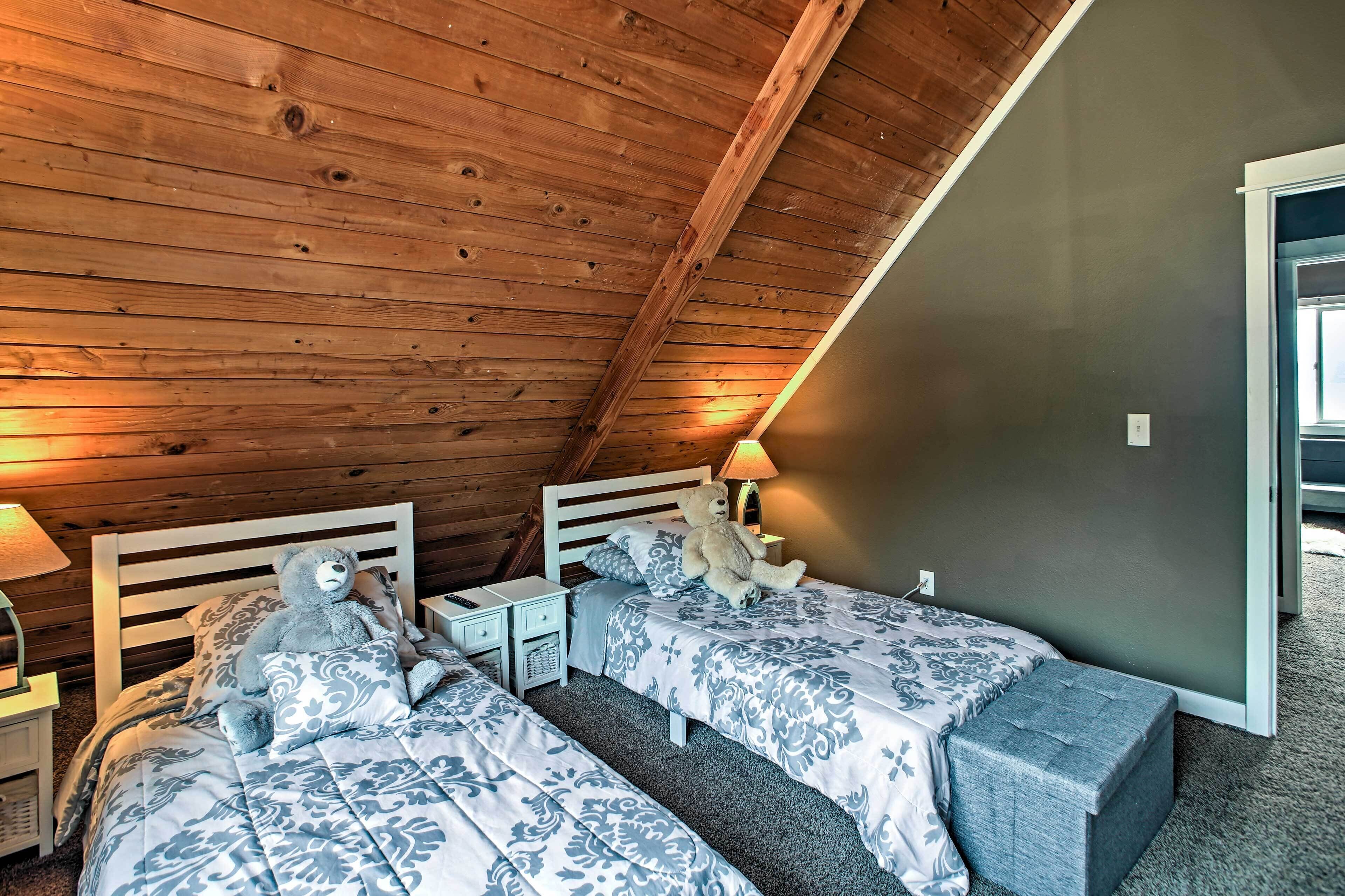 Ein Schlafzimmer mit zwei Betten, Holzbalkendecke und einem Nachttisch mit Lampe.
