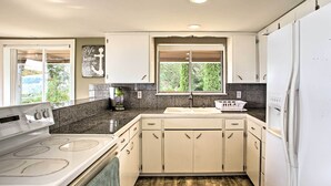 A modern kitchen with white cabinets, a built-in oven, a sink, and a refrigerator.