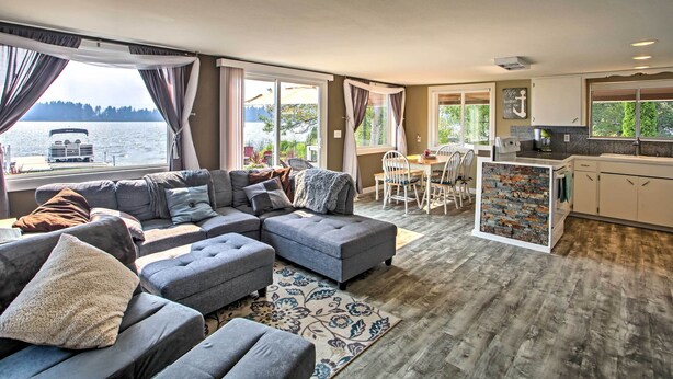 A modern living room with a sectional sofa, a dining area, and a kitchen.