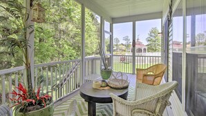 A covered porch with wicker furniture, a table, and a potted plant.
