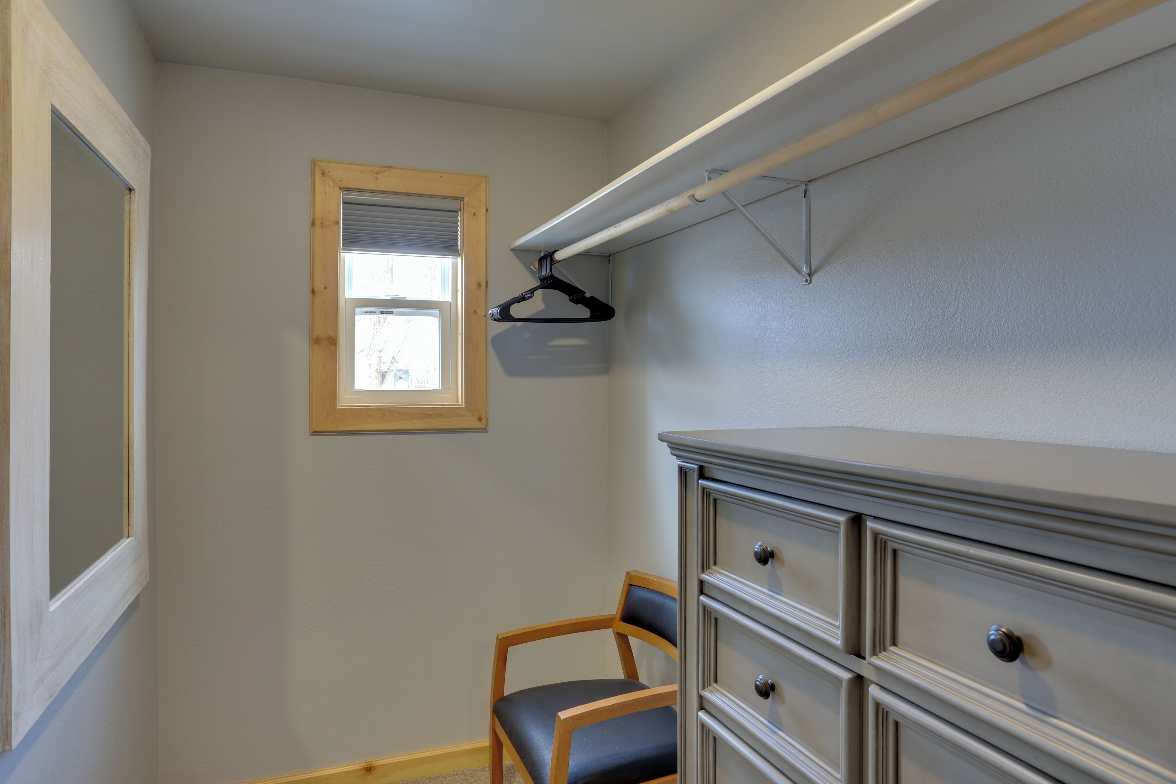 Habitación con armario empotrado, una silla y ventana con persianas.