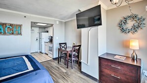 Una camera da letto con un letto, una scrivania con sedie, una TV e un comò.