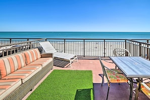 Un balcon avec un canapé en osier, une table et une chaise, donnant sur une plage.