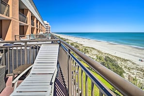 Un balcon avec des chaises longues donnant sur une plage.