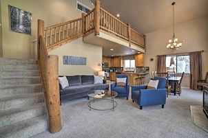 Un espacio habitable amplio con una escalera que conduce a un nivel superior, una cocina al fondo y un comedor con muebles de madera.