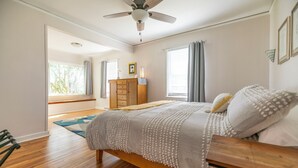 A bedroom with a wooden bed, a ceiling fan, and a view of the outdoors.