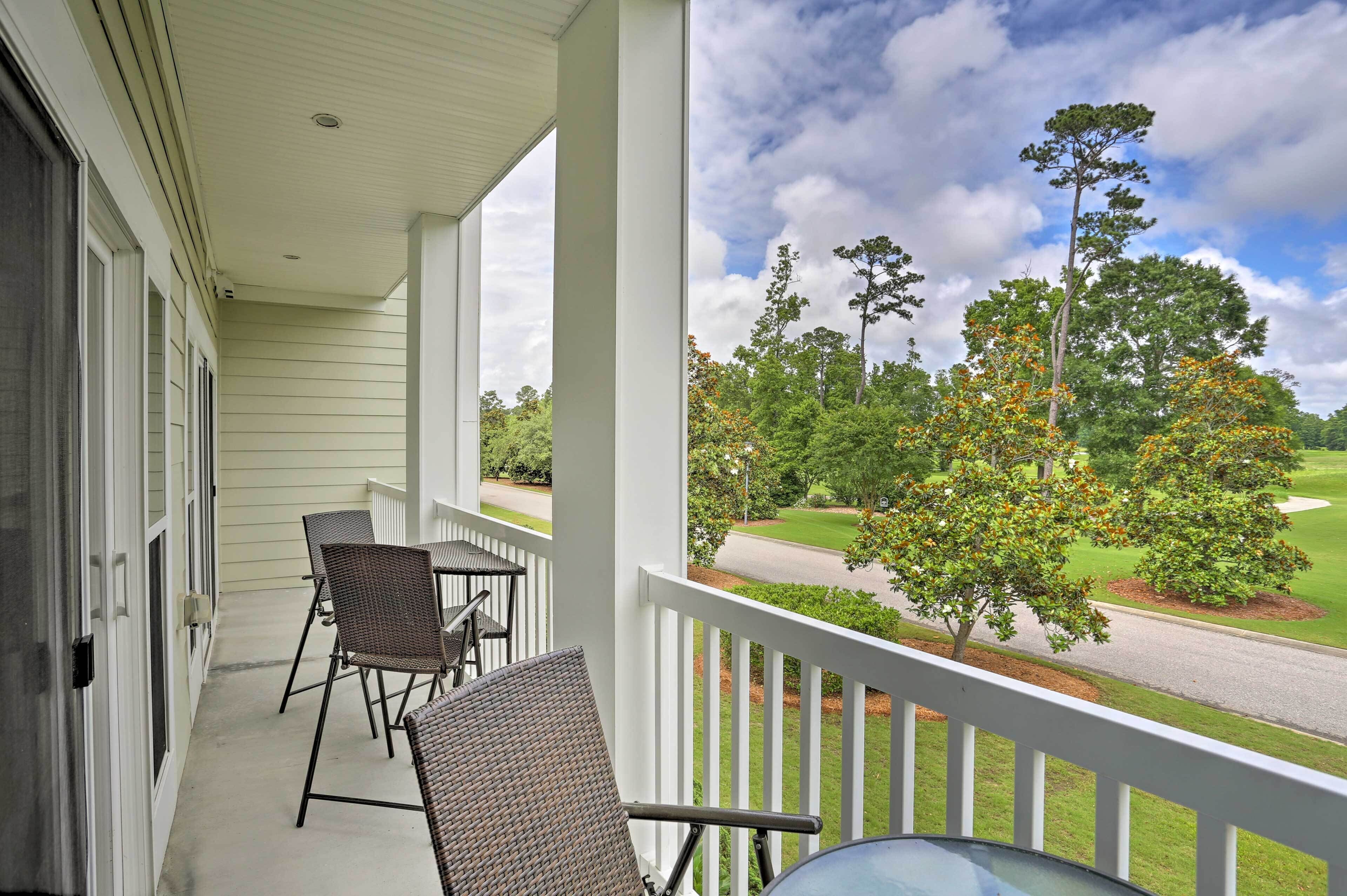 A covered porch with wicker furniture and a view of a golf course.