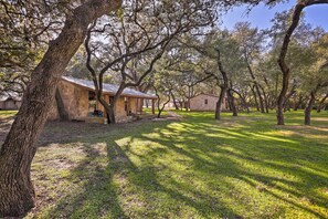 A rustic building with a stone exterior, surrounded by a well-maintained lawn and large trees. - Blanco Riverfront Historic Home, 3 Mi to Downtown! (Blanco)