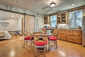 A modern kitchen with wooden cabinets, a marble backsplash, and a dining area with red upholstered chairs. - Blanco Riverfront Historic Home, 3 Mi to Downtown! (Blanco)