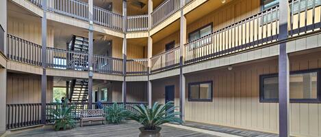 A multi-level atrium with wooden flooring, balconies, and potted plants.