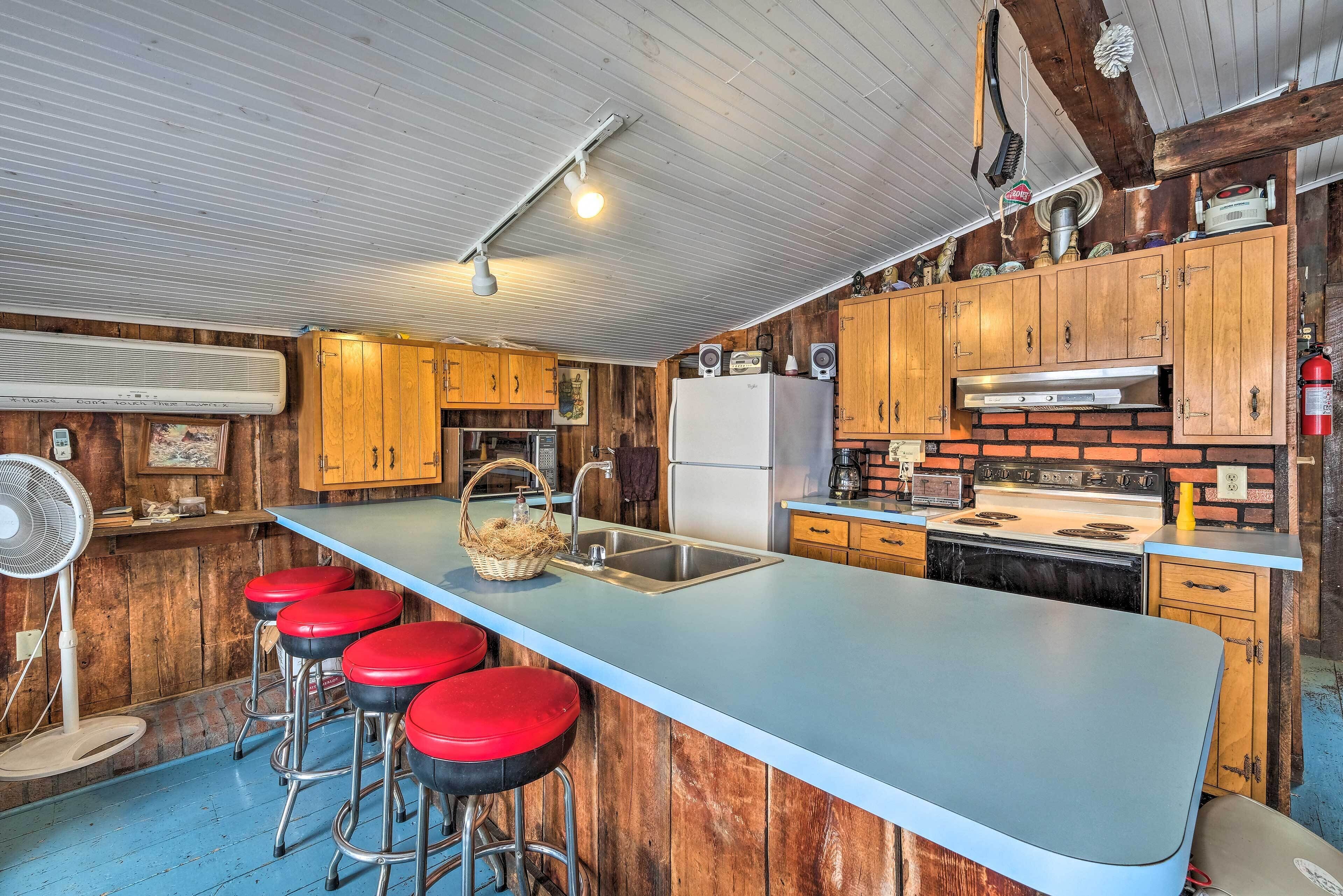 Une cuisine dotée d’un îlot central, de tabourets de bar, de meubles en bois, d’un réfrigérateur et d’une cuisinière.