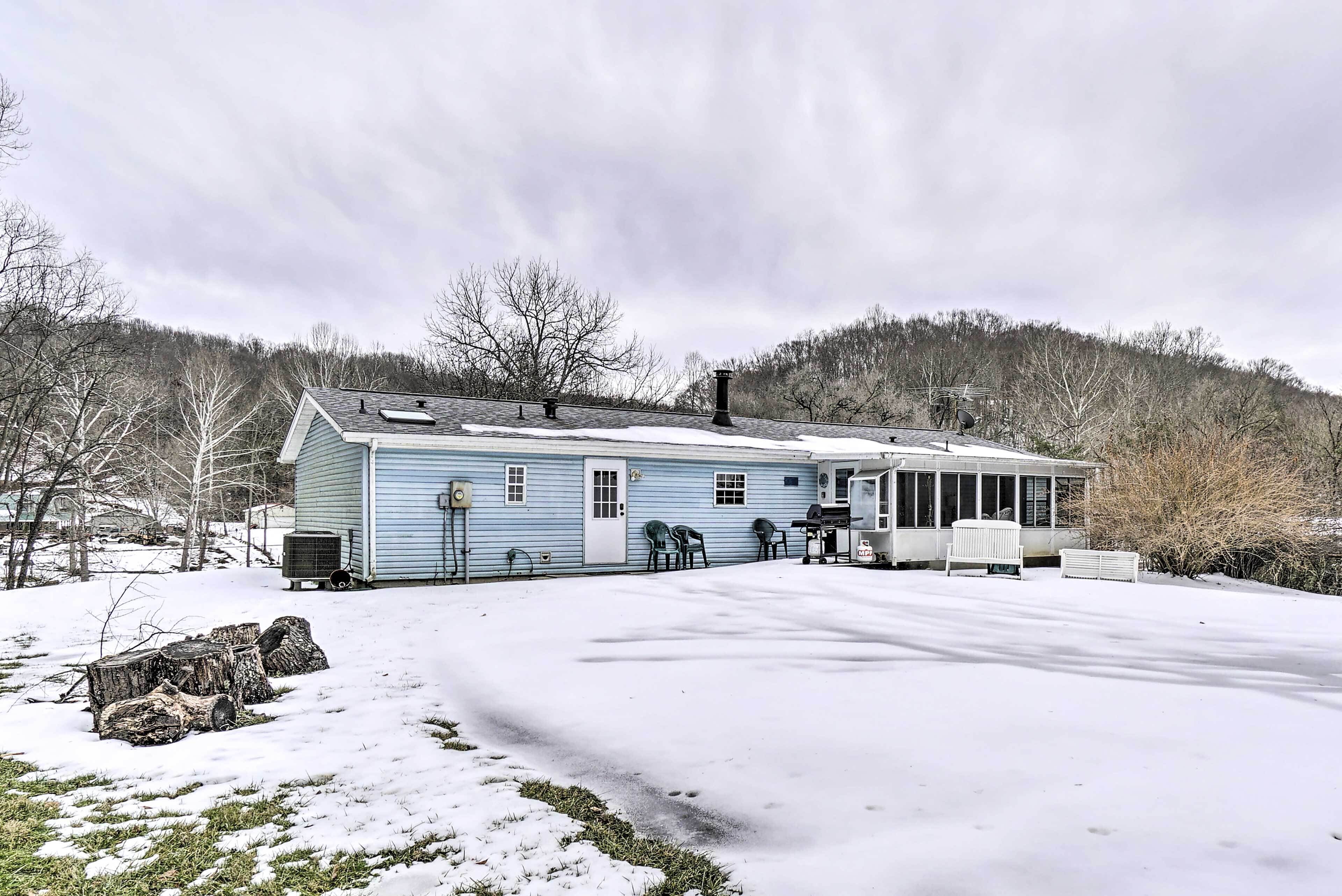 A two-story house with a garage, a covered porch, and a snow-covered yard.