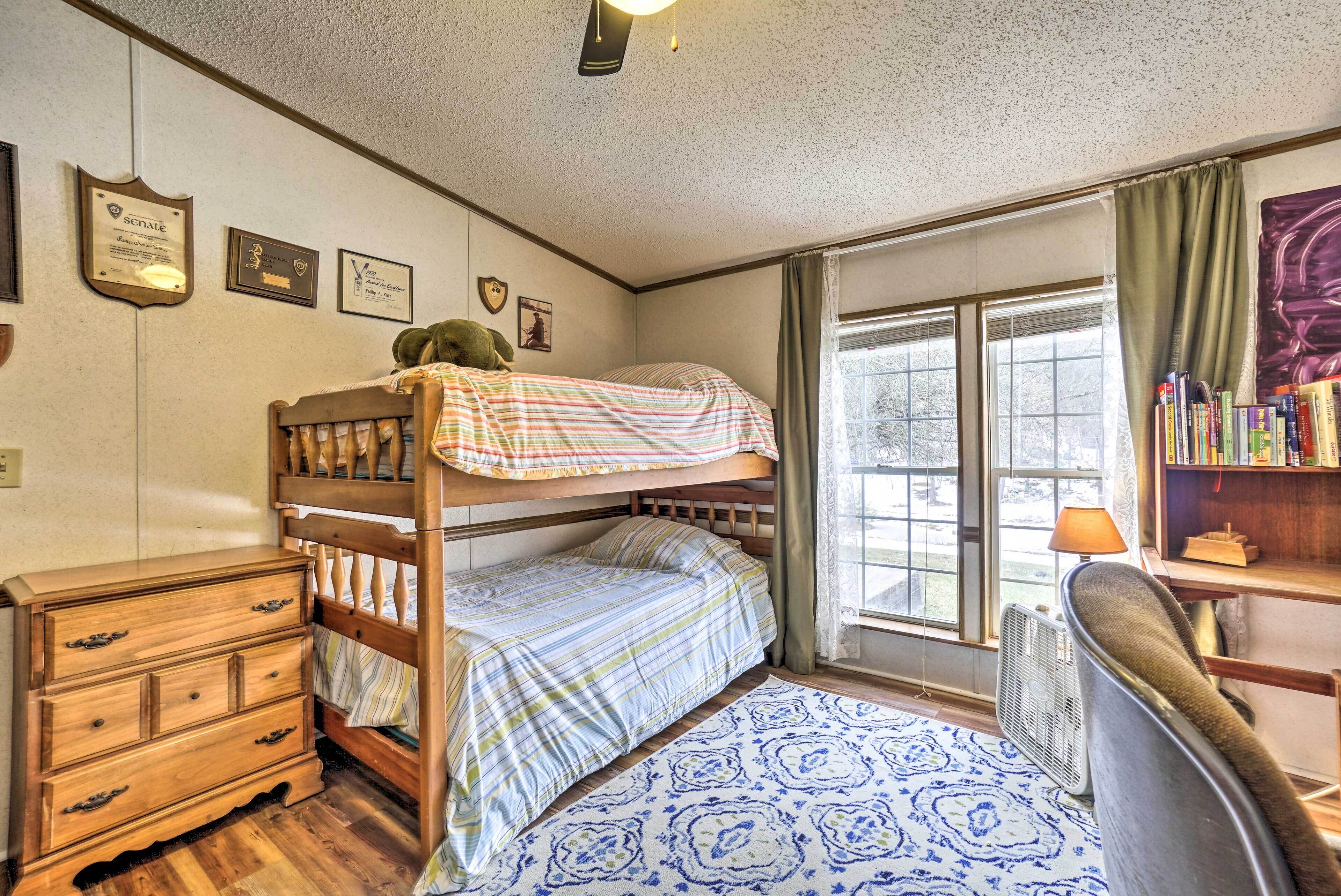 A room with bunk beds, a wooden dresser, a radiator, and a bookshelf.