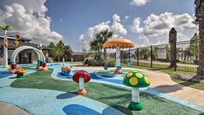 Une aire de jeux dotée d’éléments de jeu colorés en forme de champignons et d’un chemin sinueux.