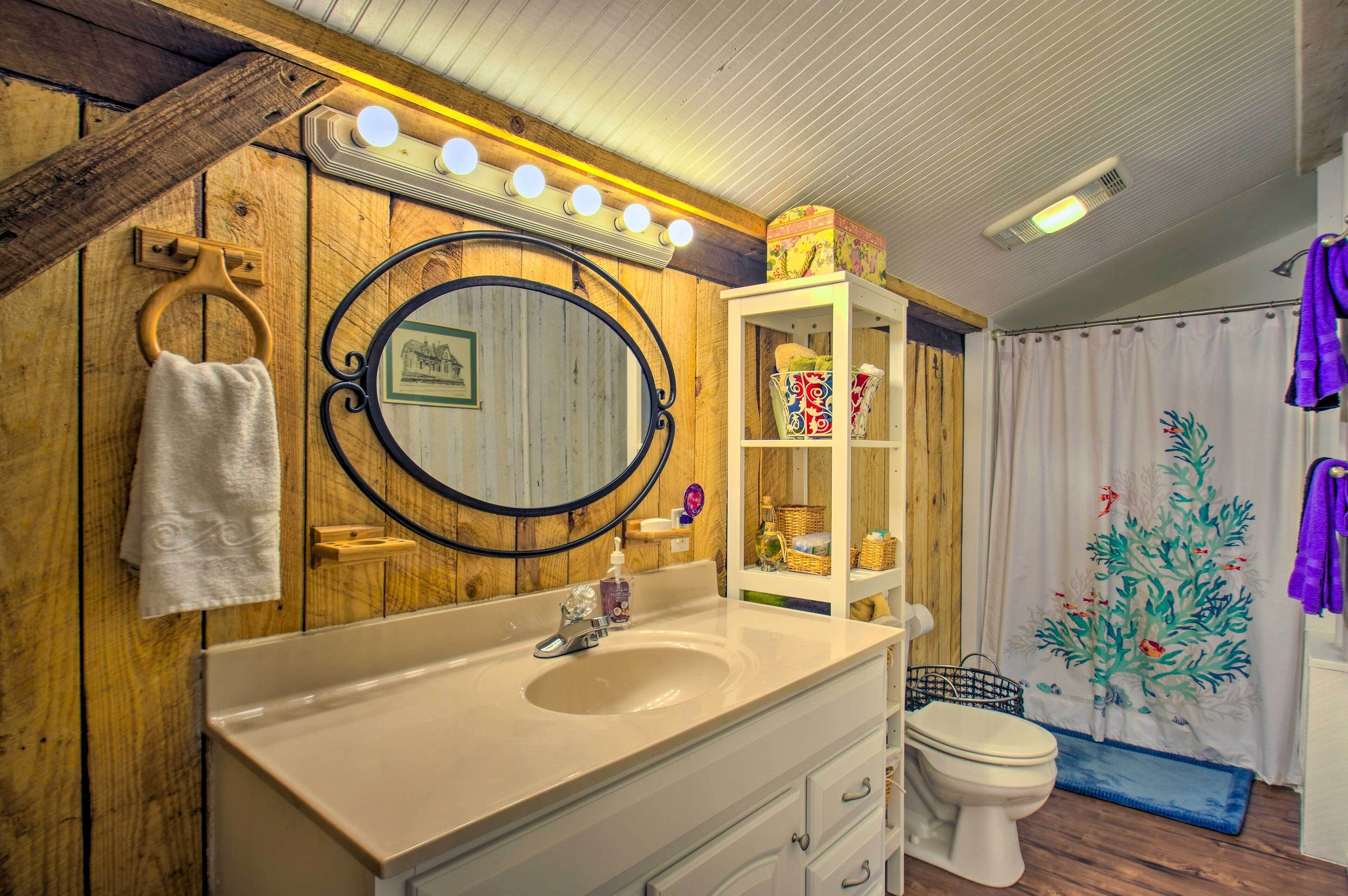 A bathroom with a wooden vanity, a round mirror, a sink, and a toilet.
