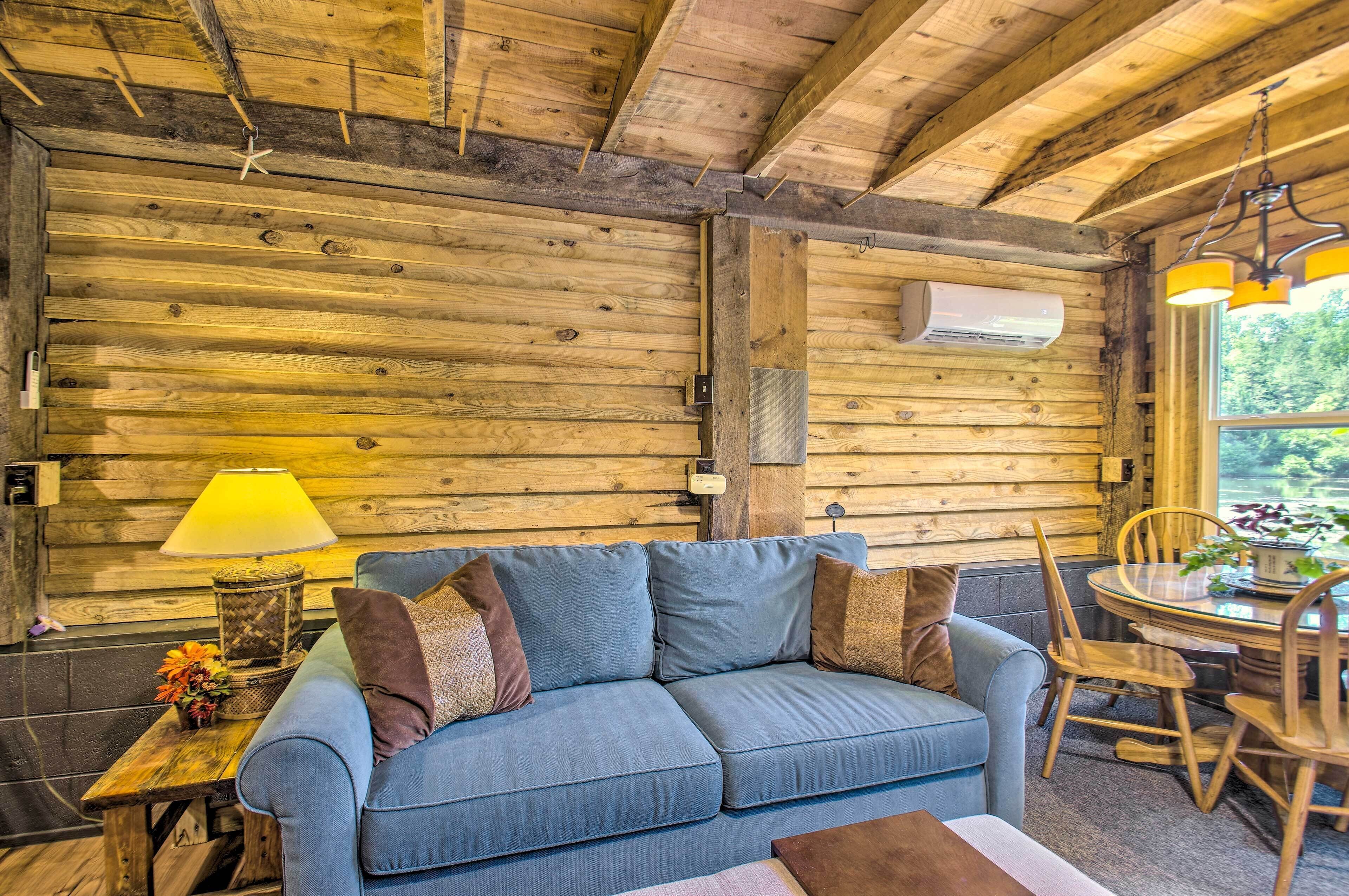 L’intérieur d’un chalet accueillant, avec un mur en bois, un canapé bleu, une table à manger avec des chaises et une lampe suspendue.