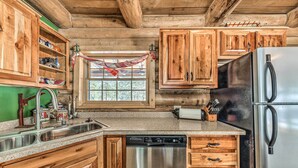 A kitchen with wooden cabinets, stainless steel appliances, and a window with a view. - Cozy Alto Cabin on 2 Acres: Near Fishing & Skiing! (Alto)