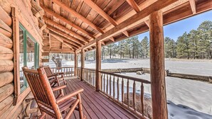 A wooden cabin with a covered porch, wooden chairs, and a view of a snowy landscape. - Cozy Alto Cabin on 2 Acres: Near Fishing & Skiing! (Alto)
