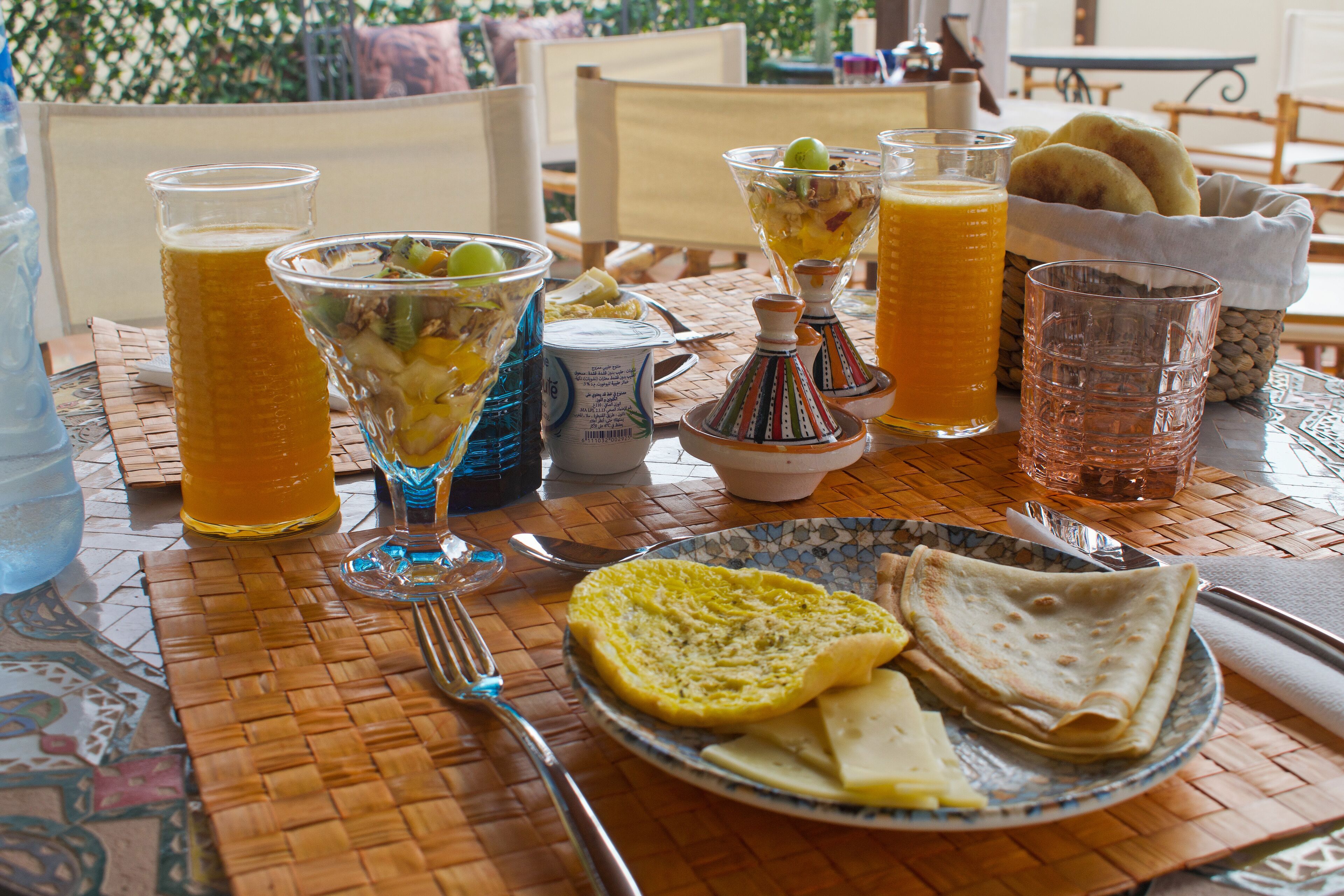 A table set with breakfast items including bread, a plate of cheese, and various drinks in glasses.