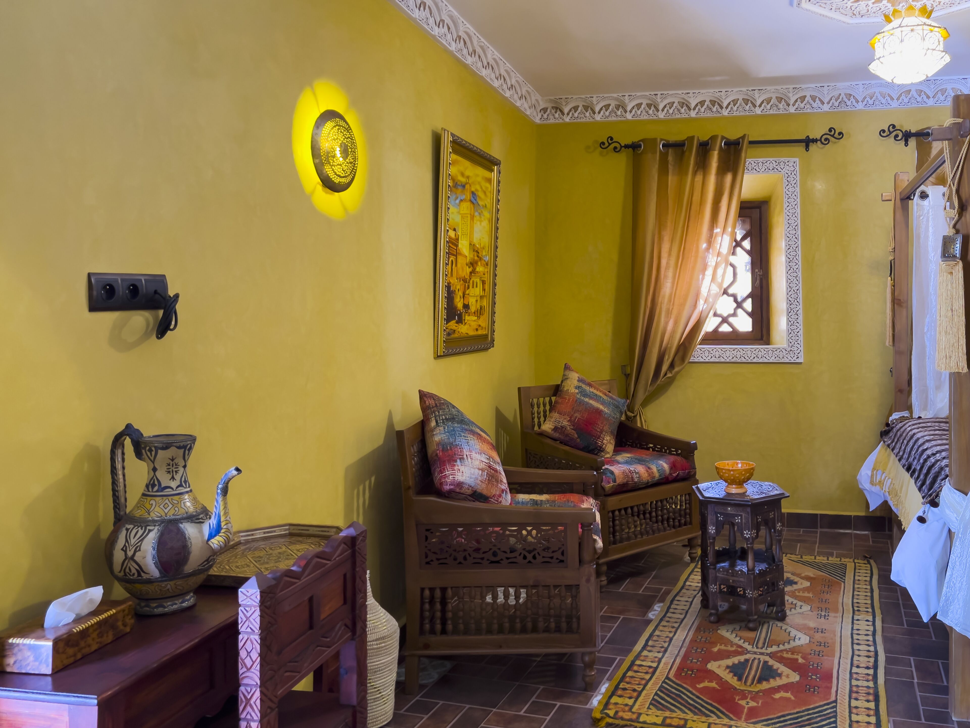 A traditional room with a patterned rug, wooden furniture, and a decorative wall hanging.