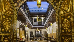 Un interior ornamentado con un espacio central abierto, arcos decorativos y faroles colgantes.