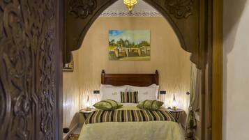 Una habitación con una cama, dos mesitas de noche, un cuadro en la pared y una lámpara decorativa en el techo.