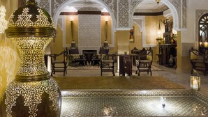 Un interior tradicional con arcos ornamentales, una fuente central y una lámpara decorativa de gran tamaño.