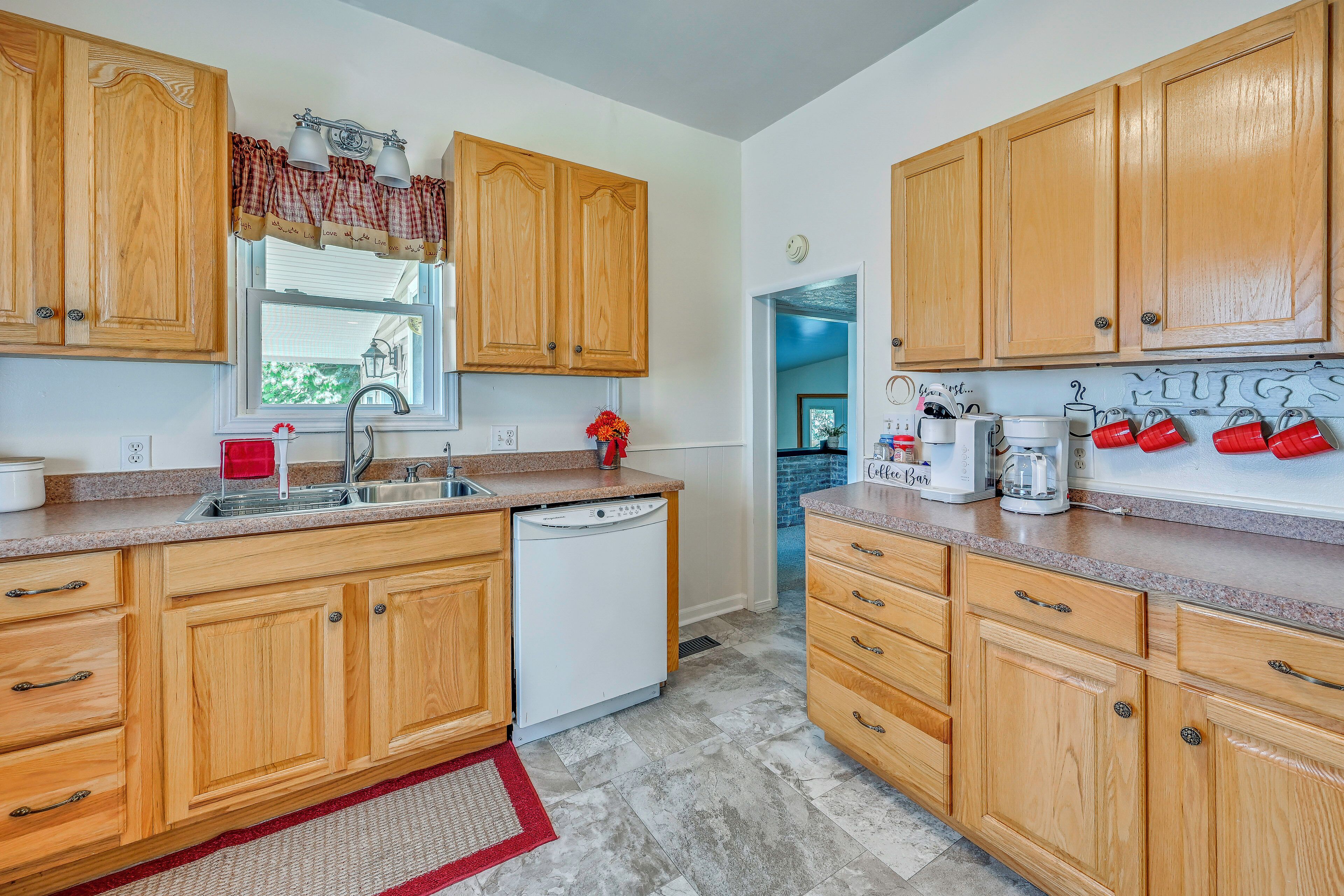 A kitchen with wooden cabinets, a dishwasher, a sink, and a countertop with various appliances.