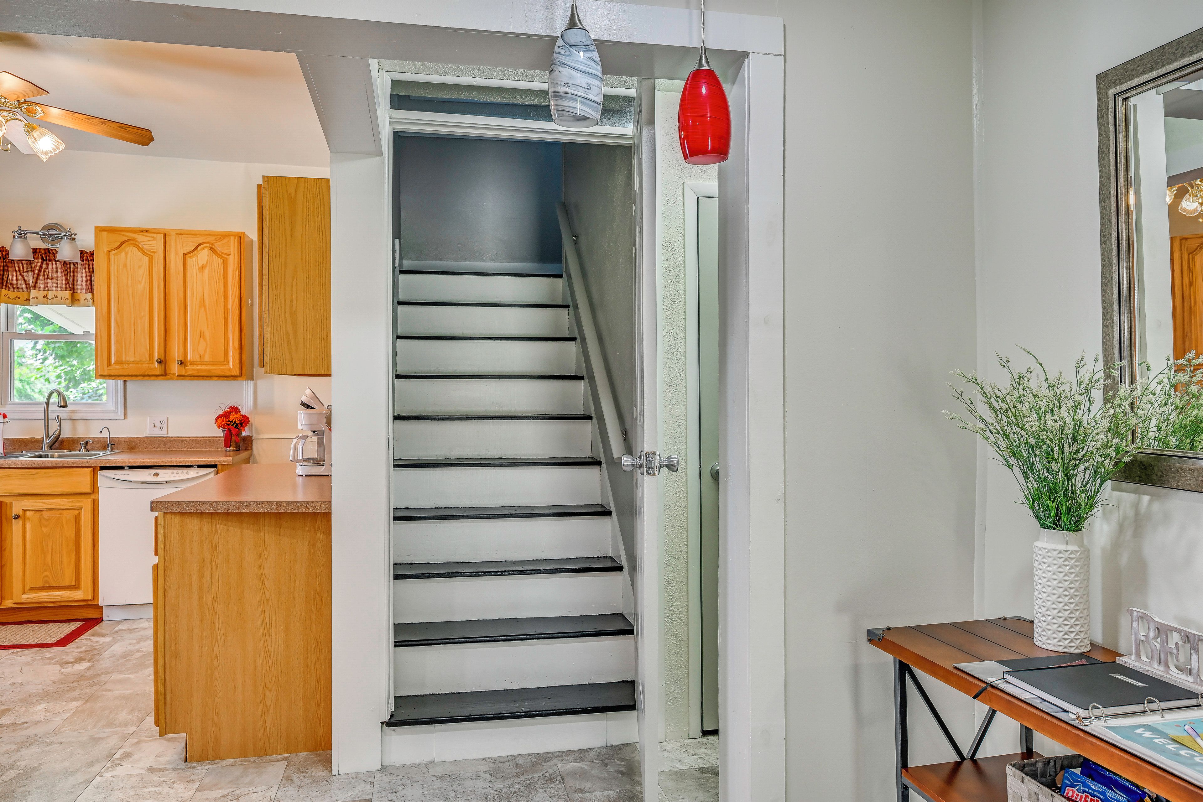 Une cuisine avec des meubles de rangement en bois, un plan de travail et un escalier menant à l’étage supérieur.