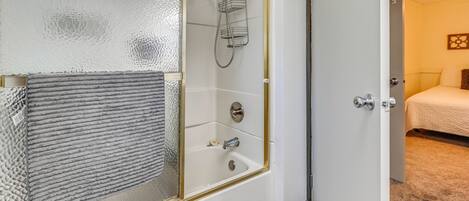 A bathroom with a glass shower enclosure, a bathtub, and a toilet.