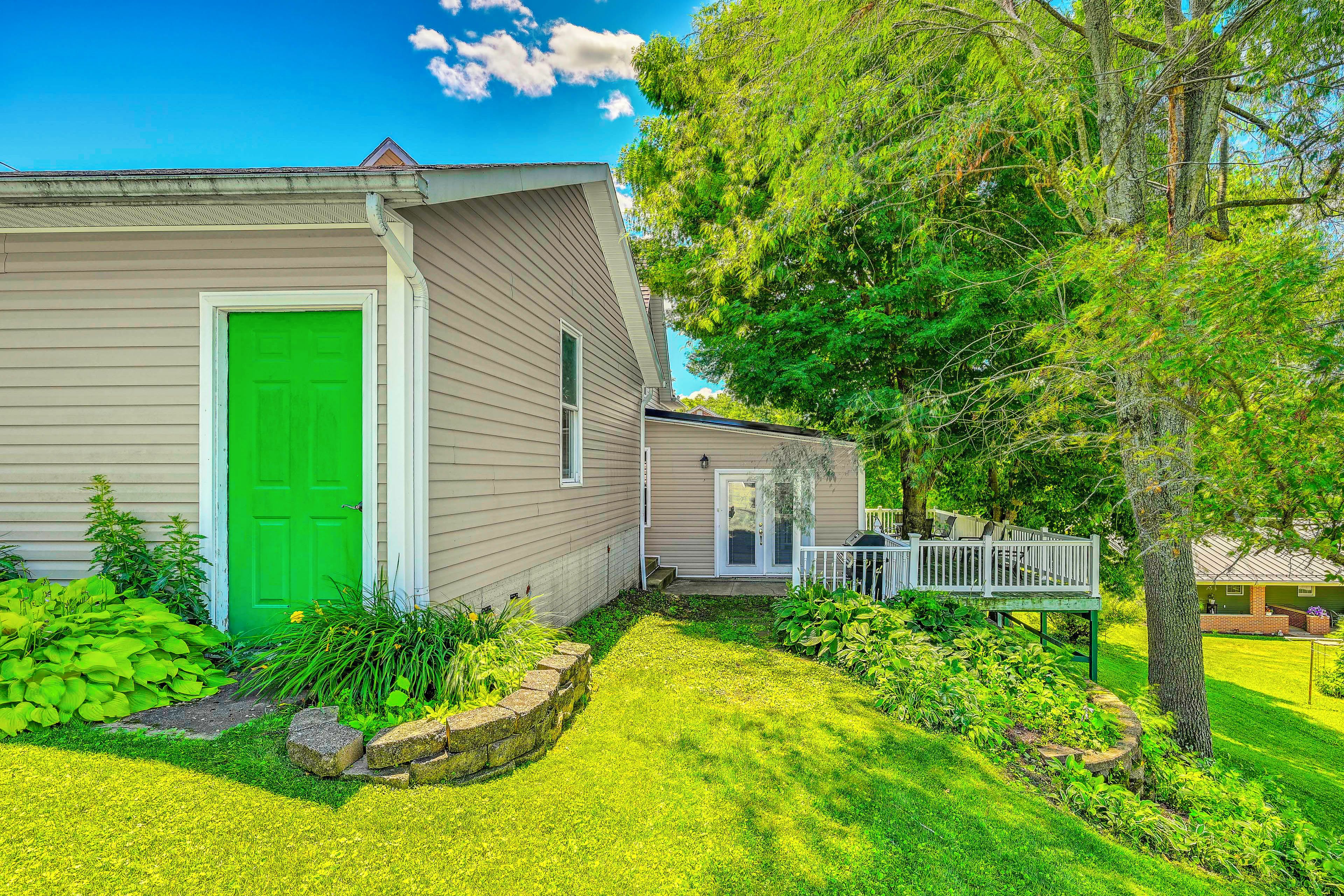 A residential house with a green door, a covered porch, and a well-maintained lawn.
