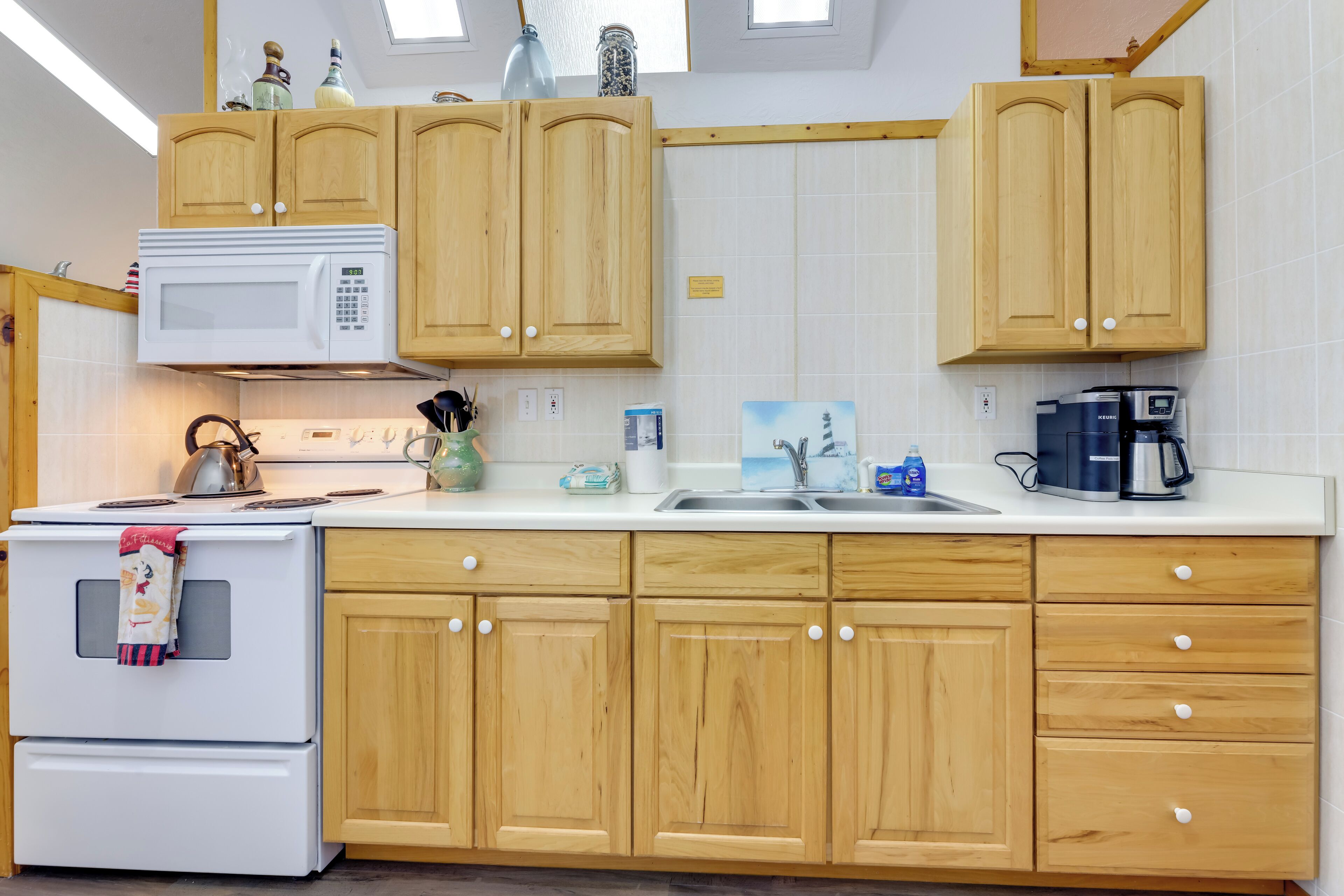 A kitchen with wooden cabinets, a white stove, a microwave, and a coffee maker.