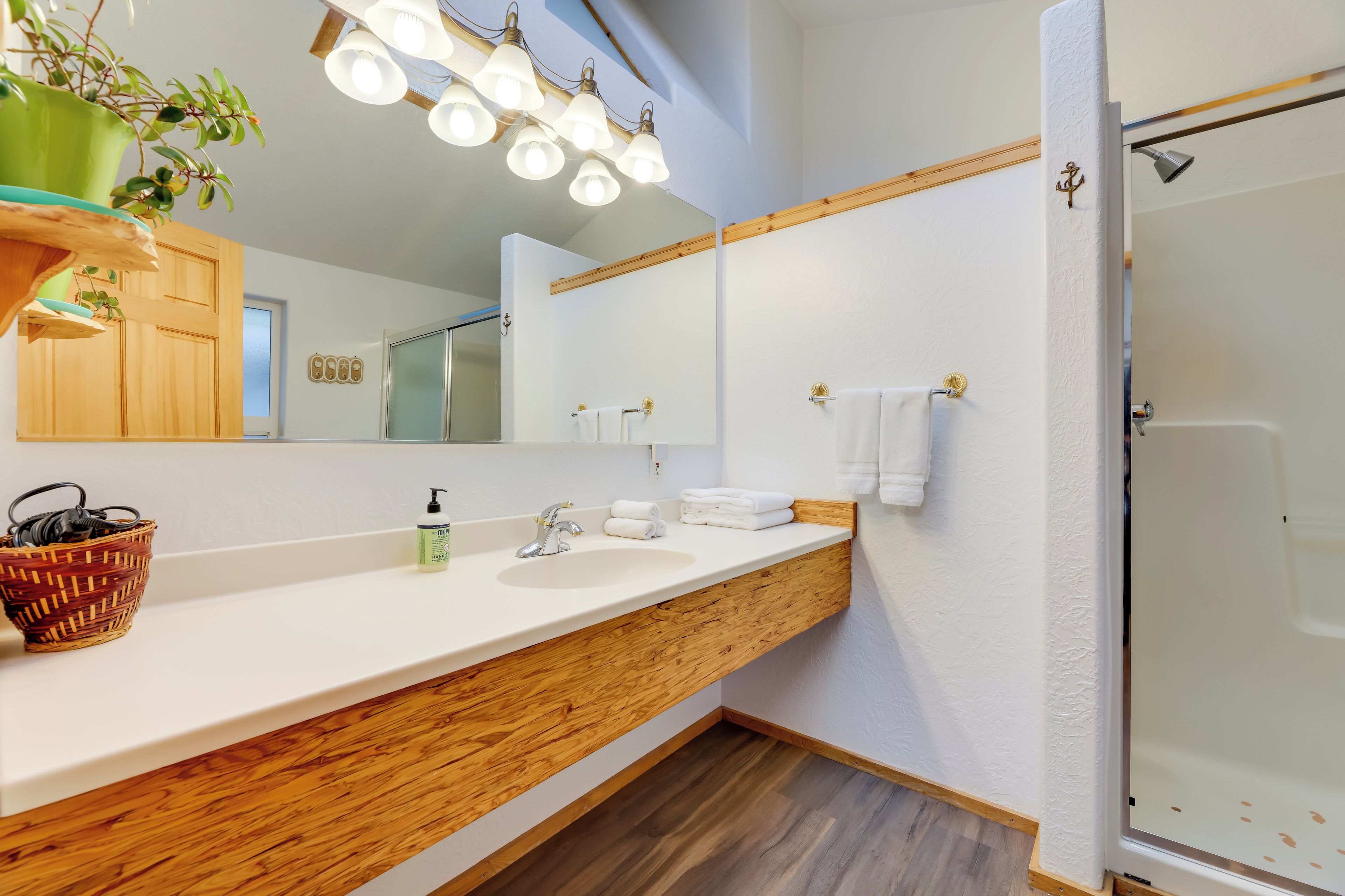 A bathroom with a wooden vanity, a large mirror, and a shower area.