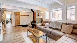 A spacious living room with a wooden floor, a brown leather sofa, a coffee table, and a fireplace. - Cozy Condo Near Golf, 7 Mi to Big Sky Resort! (Big Sky)