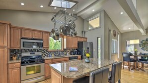 Une cuisine moderne dotée de plans de travail en granit, d’appareils électroménagers en acier inoxydable et d’armoires en bois.