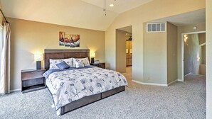 A bedroom with a bed, nightstands, a ceiling fan, a painting, and a hallway leading to a bathroom. - Waterfront Discovery Bay Home: Outdoor Bar & Dock (Discovery Bay)