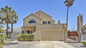 A two-story house with a garage, surrounded by palm trees and a well-maintained garden. - Waterfront Discovery Bay Home: Outdoor Bar & Dock (Discovery Bay)