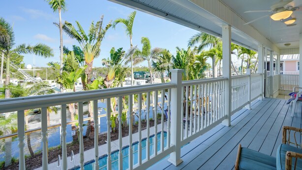 A covered outdoor area with a pool, palm trees, and a view of a parking area. - Bokeelia Island Oasis: Waterfront, Private Dock! (Bokeelia)