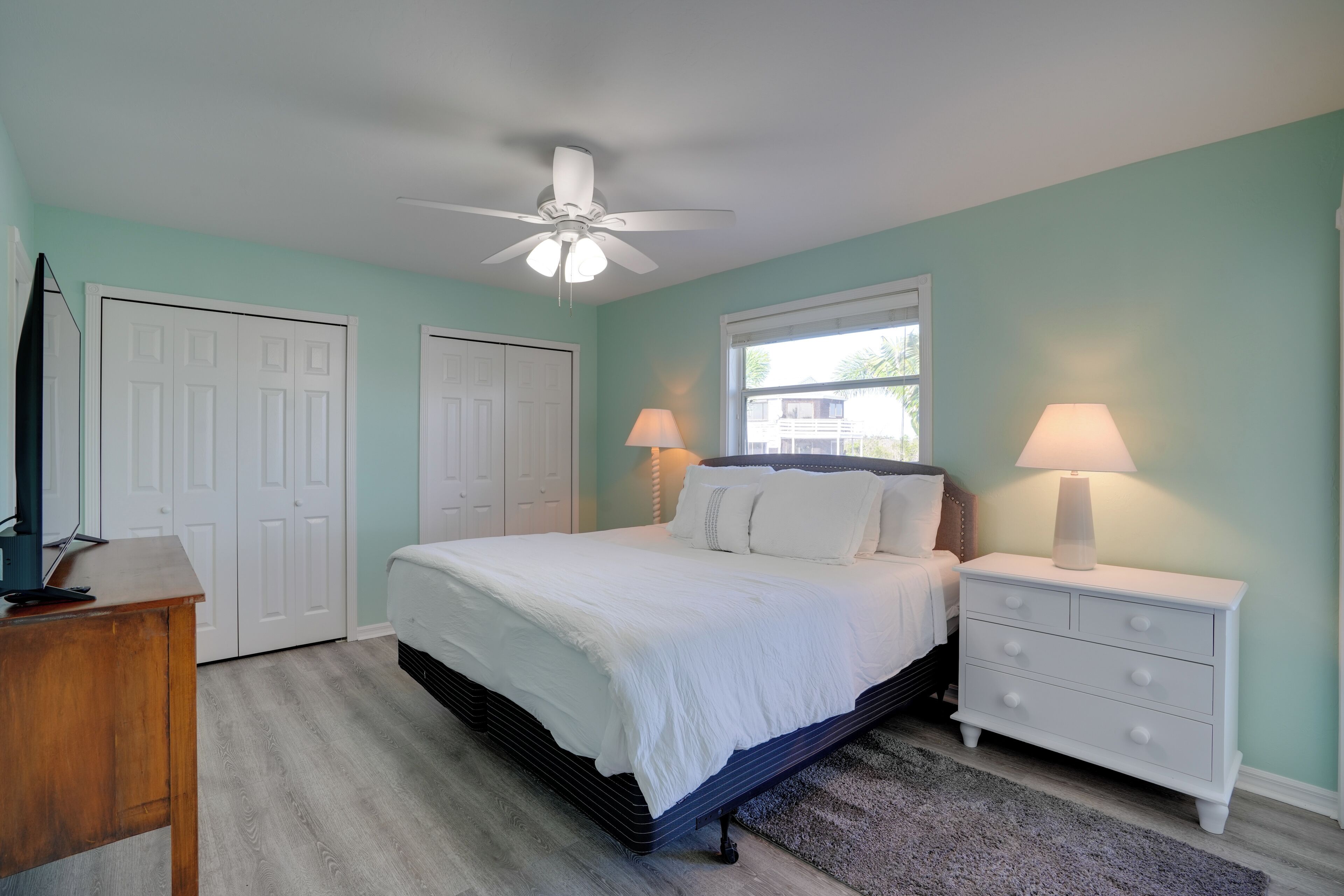 A bedroom with a bed, bedside tables, a ceiling fan, and a window.
