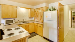 A kitchen with wooden cabinets, a white refrigerator, a microwave, and a stove. - Main Street Townhome - 12 Miles to Bear Lake! (Paris)