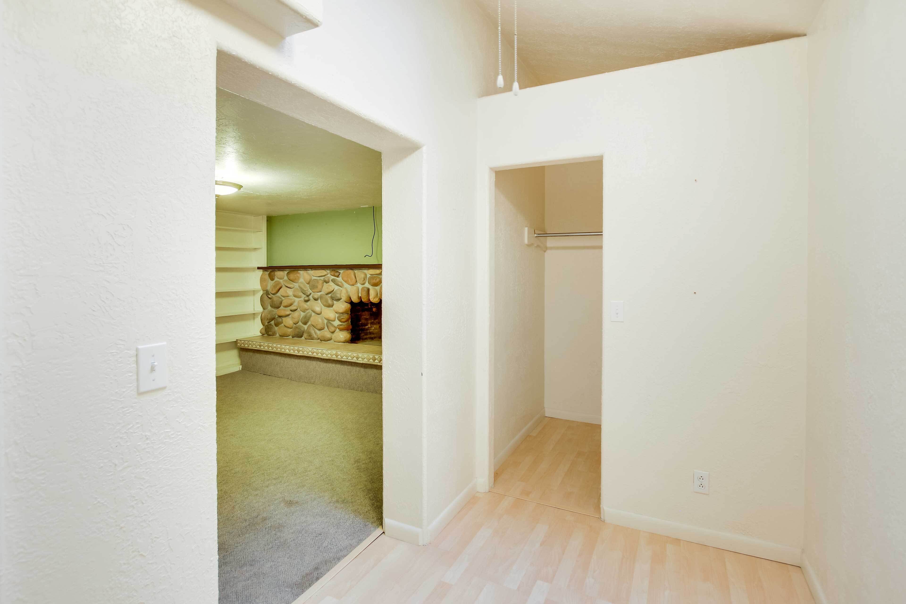 Un pasillo con alfombra que lleva a una habitación con pared de piedra y un banco de madera.