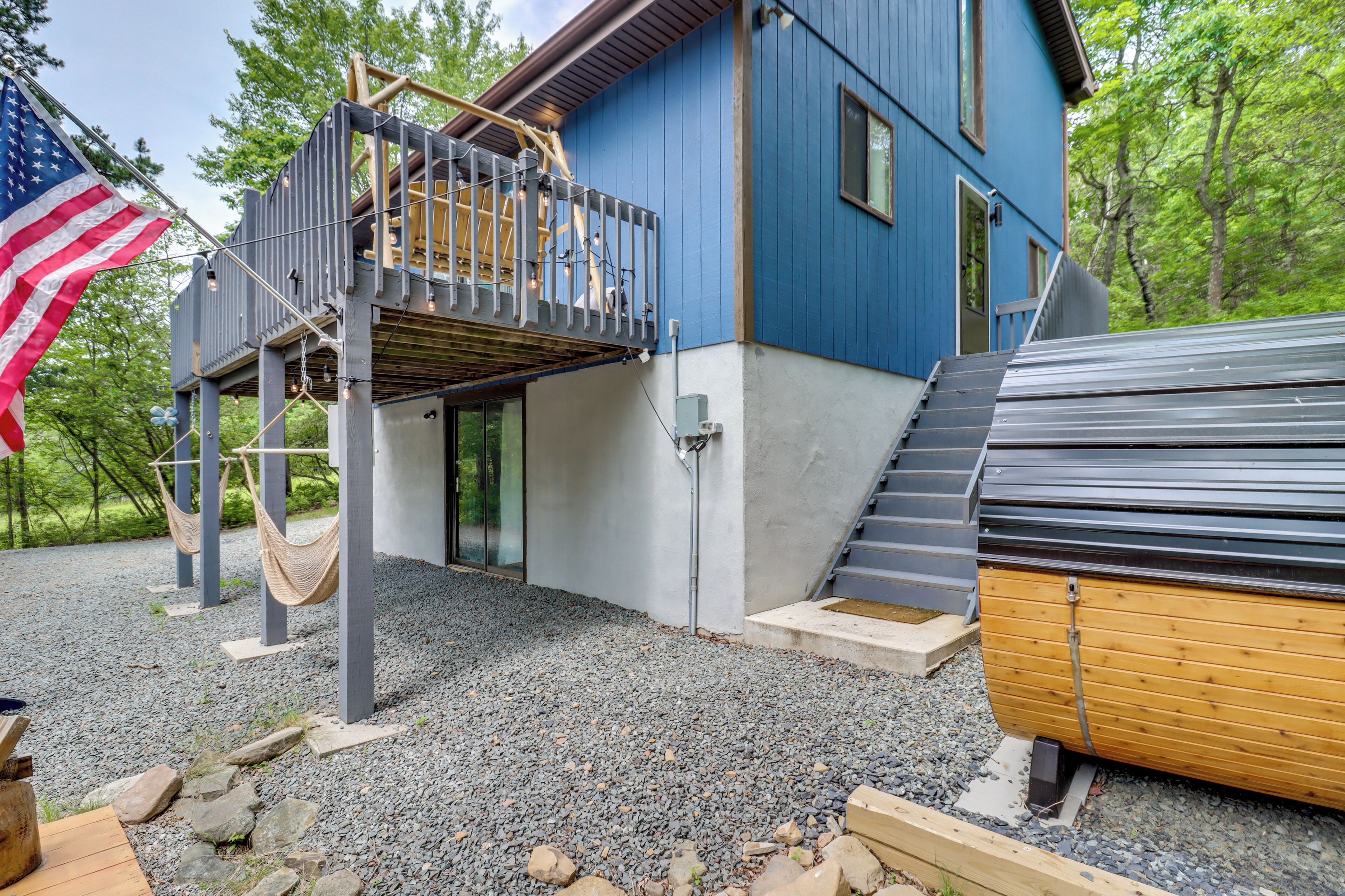Una casa moderna con facciata blu, un pontile in legno e una grande bandiera americana.